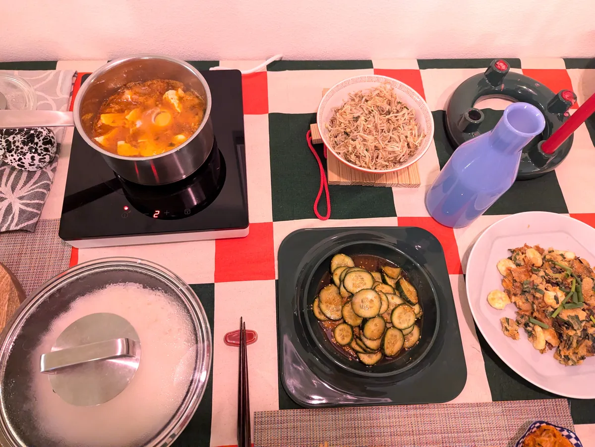 Plates of Korean banchan are displayed against a checkered table cloth.