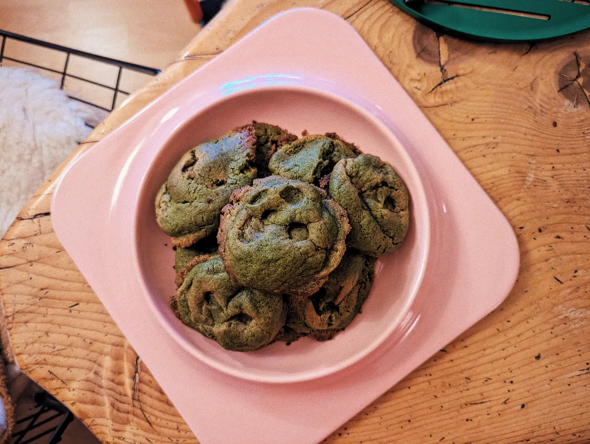 A pink plate filled with lumpy, green cookies.