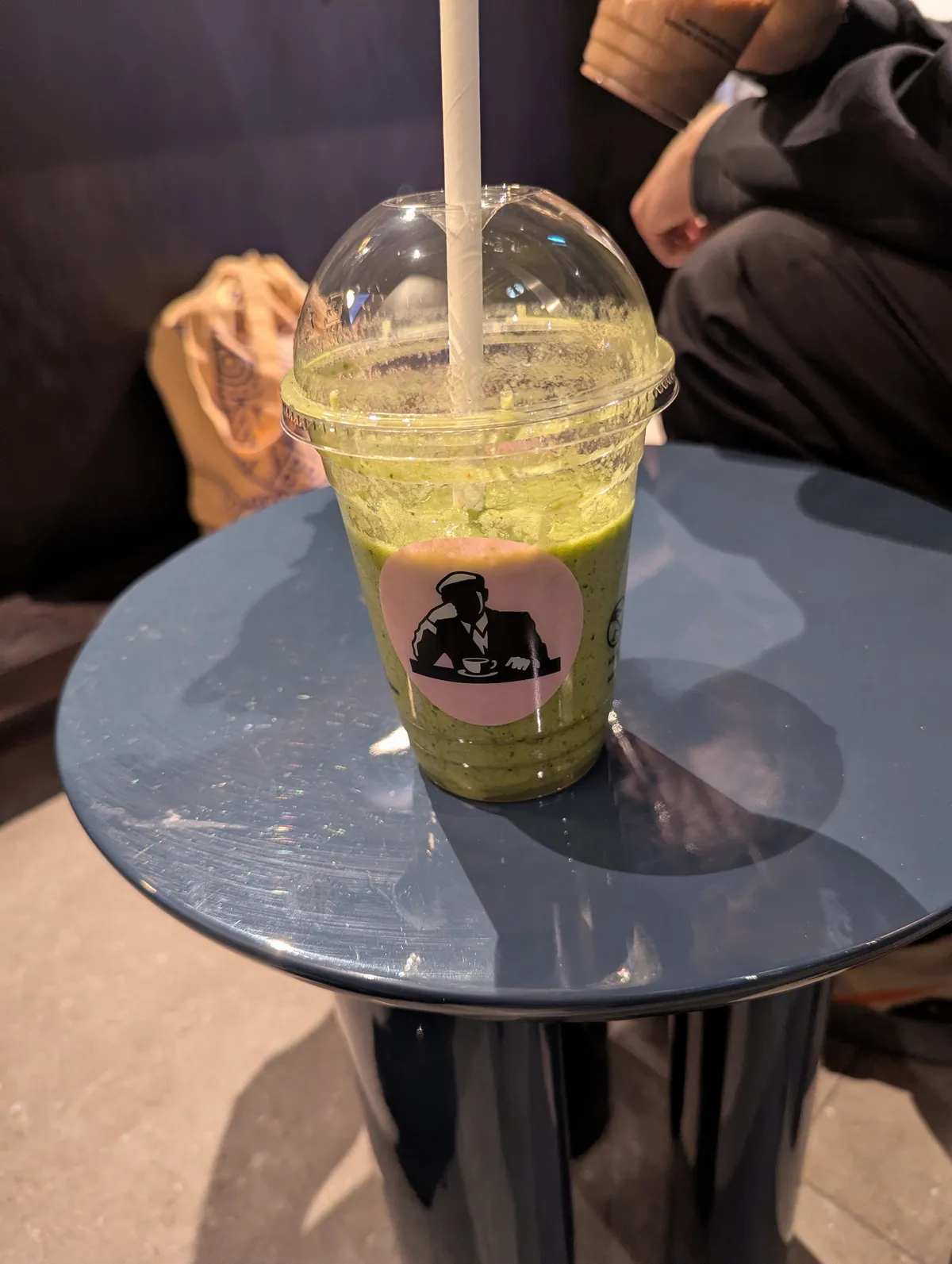 A clear, plastic cup filled with a green juice and a pink Joe and the Juice sticker slapped on the front.