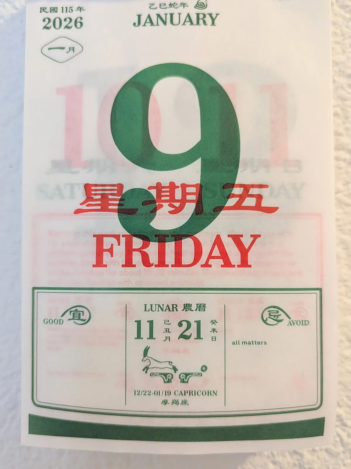 Close-up of a Chinese tear-off calendar with the date, Friday January 9 printed on it. 9 is large and red. There are fortunes towards the bottom of the page, one that says to “avoid all matters.” 