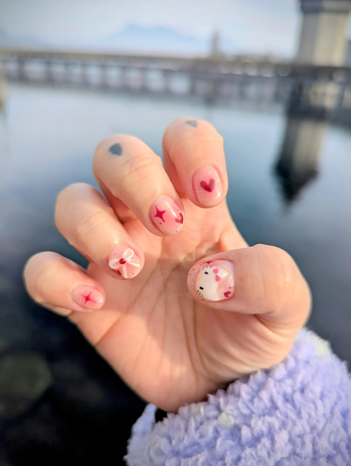A set of pink and red hello kitty themed nails on Peige's right hand.