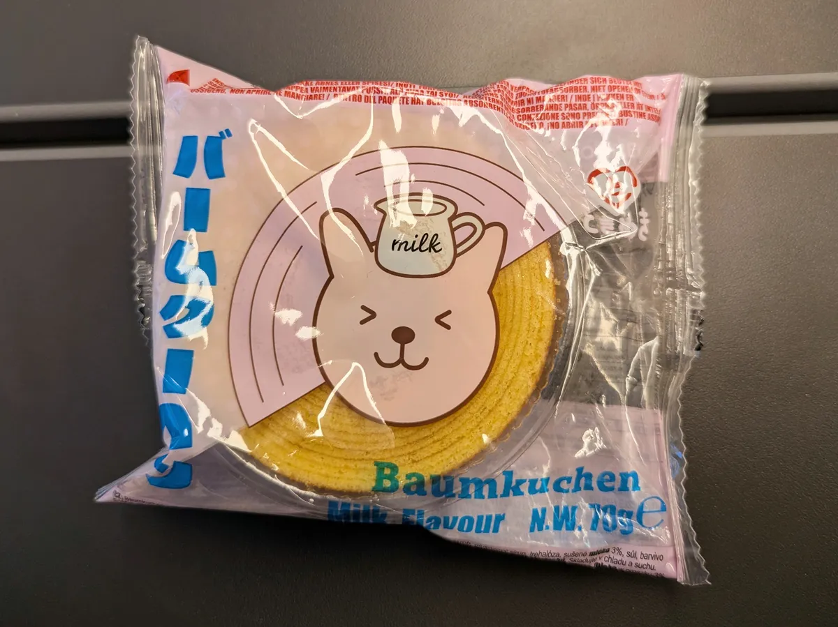 Plastic wrapped roll pastry with a winking cartoon dog with a milk bottle on its head.