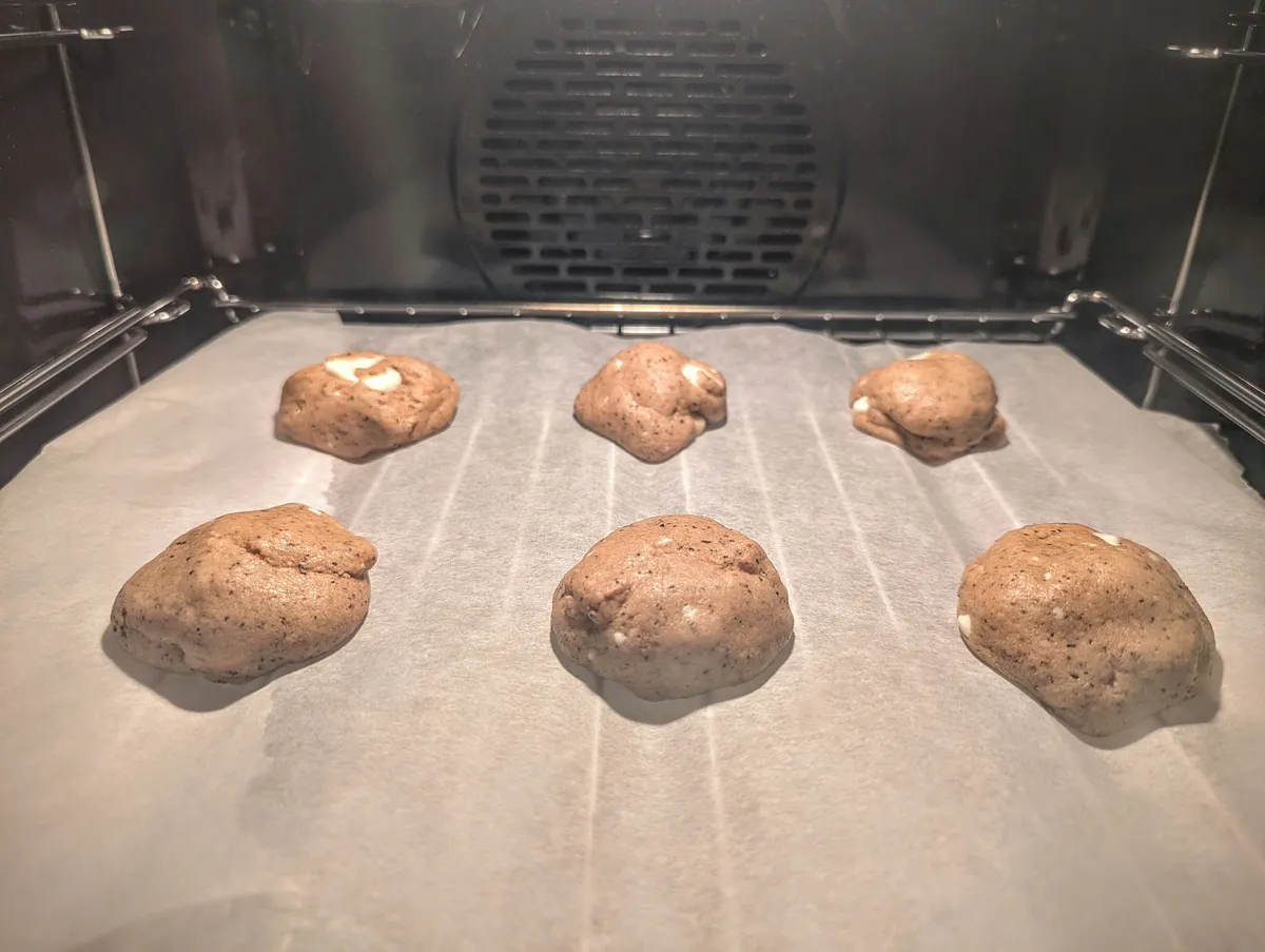 6 brown cookies baking inside the oven.
