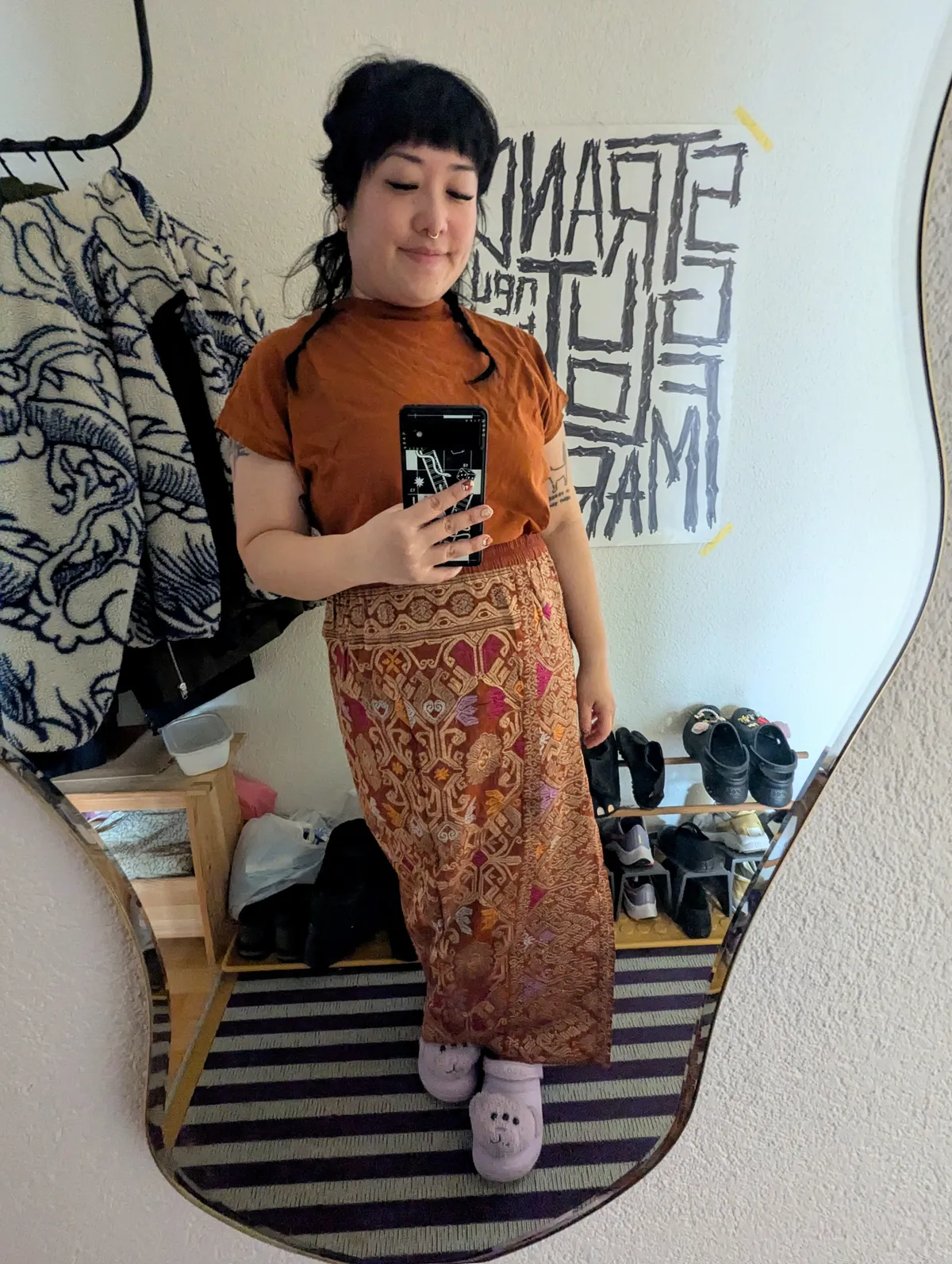 Peige wearing a golden brown shirt and a maxi length brown skirt with ornate gold embroidery.