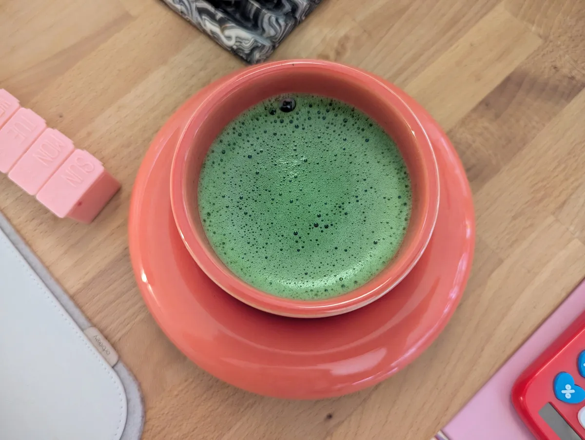 Foamy matcha in a red Gustav Westman matching cup and saucer.