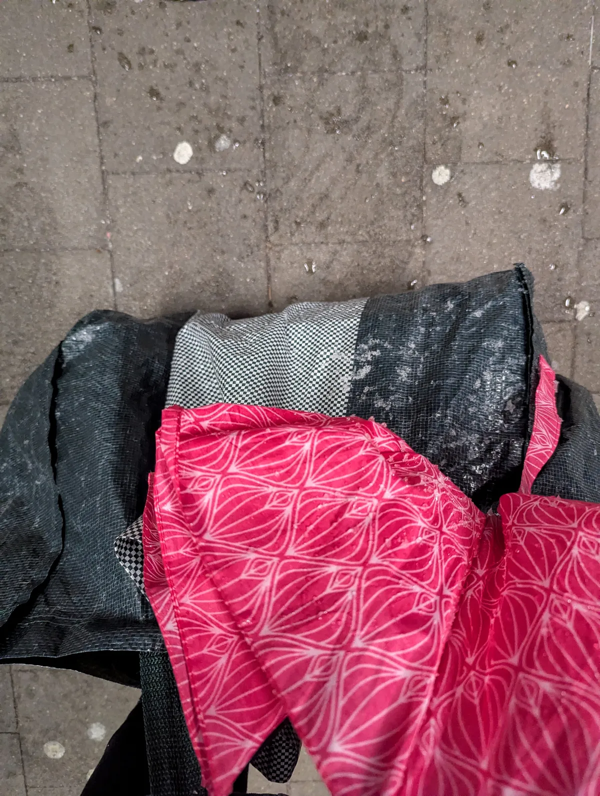 Green Ikea bag and pink umbrella with bits of slushy snow.