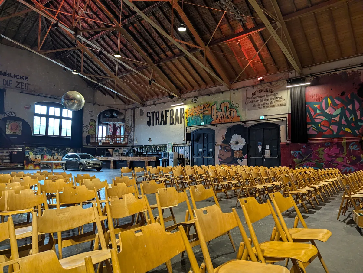A row of wooden chairs inside and urban warehouse environment with murals on the walls.