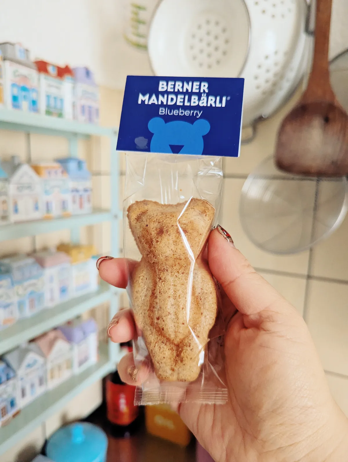 Peige holds a packaged little bear cake in their kitchen. The packaging states that the flavor is blueberry.