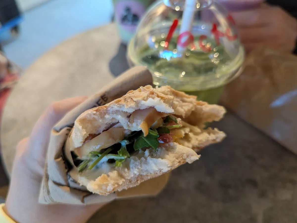 Peige holding a sandwich that's been bitten.
