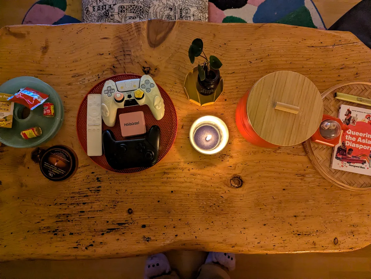 A wooden coffee table with some decor on it, and a lit candle.