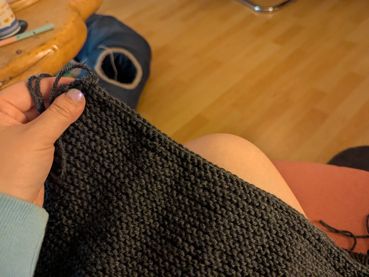 Peige holding a dark grey knitted piece.