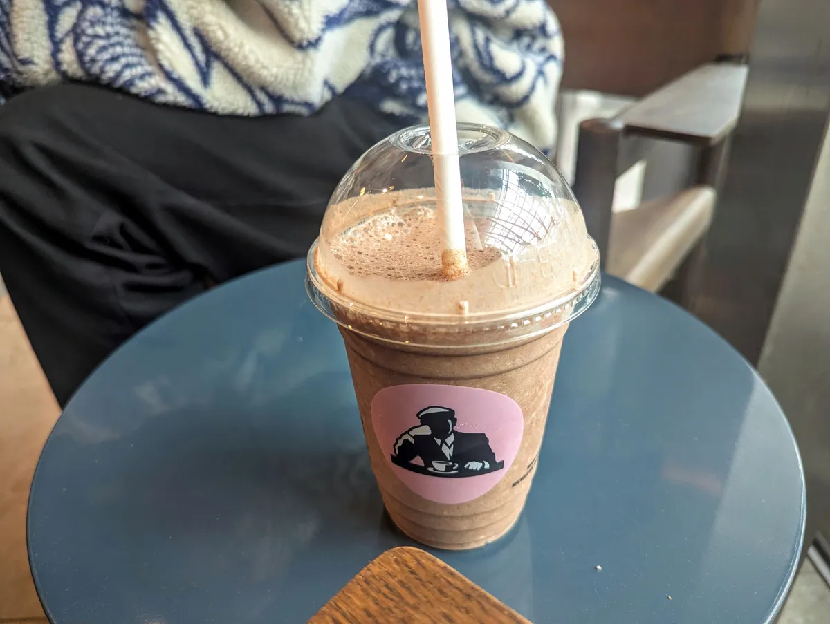 A chocolate smoothie from sitting on a blue side table.