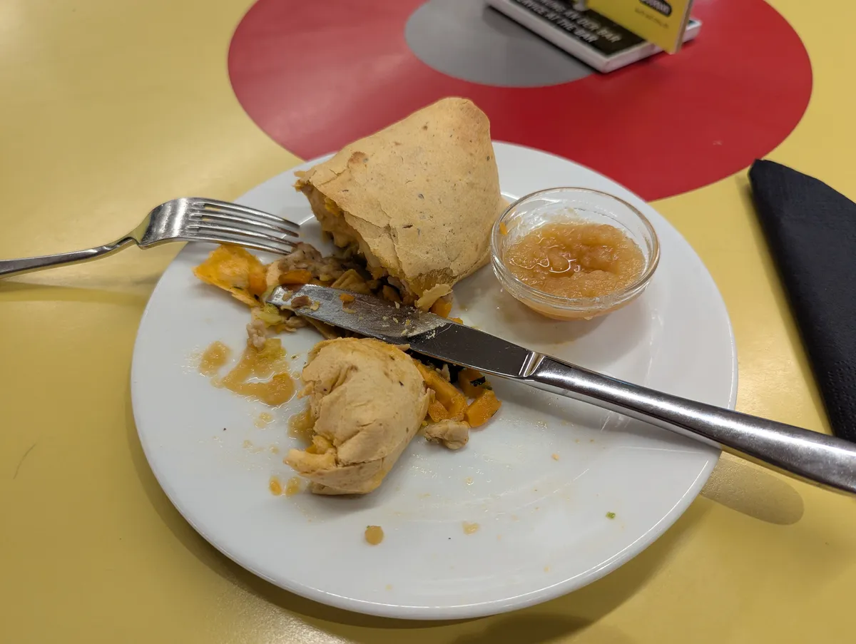 A cut-open sweet potato and chicken roll with sauce on the side.