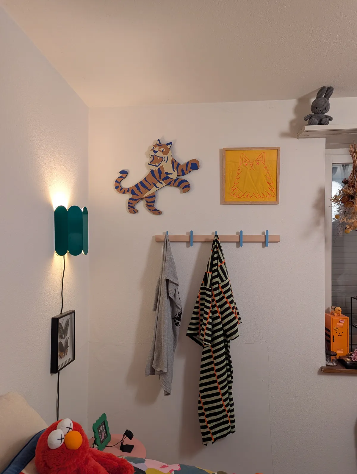 A corkboard shaped like a tiger with blue stripes next to a framed illustration of a red dog on a yellow background.