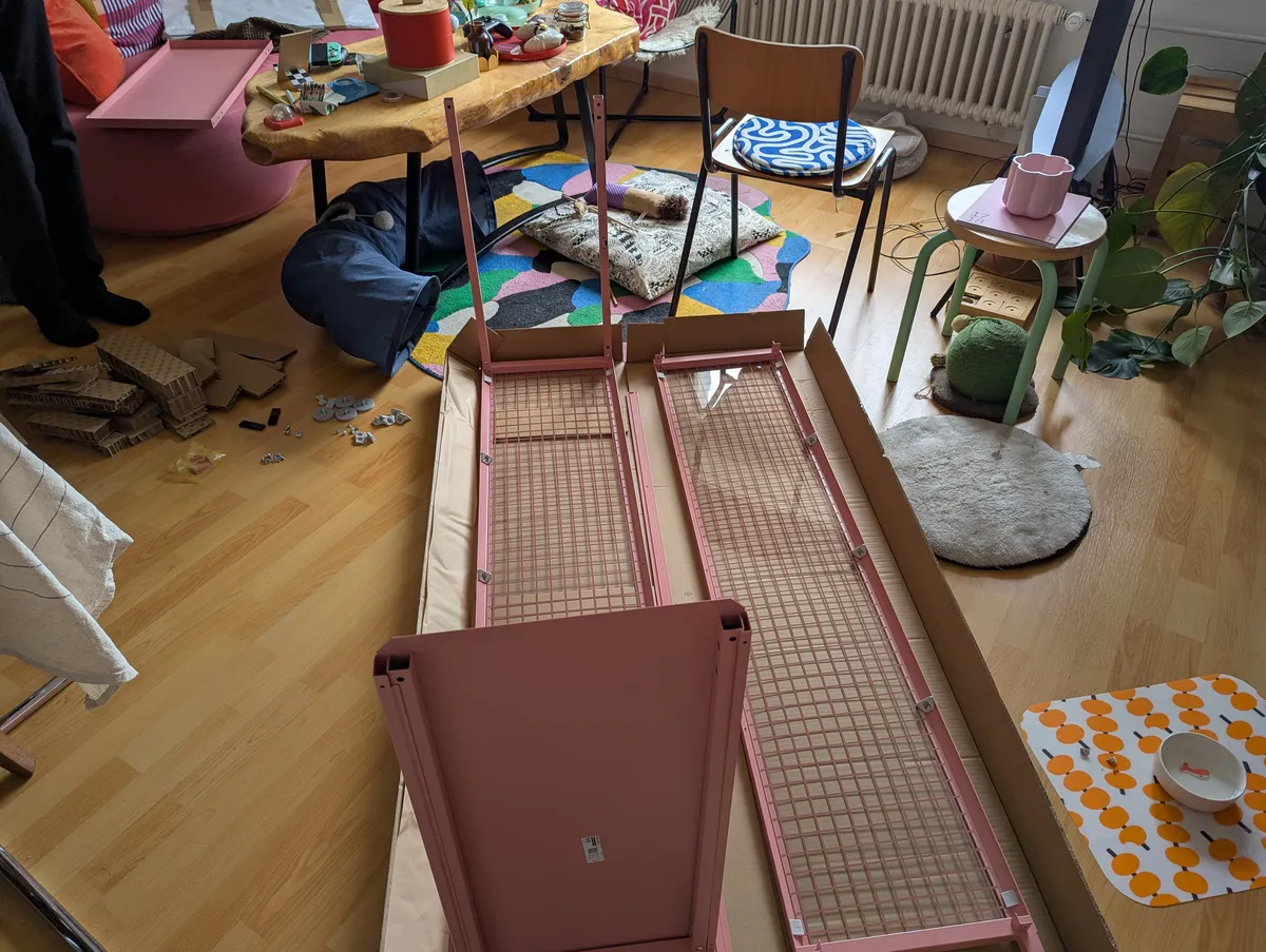 A pink Ikea cabinet being built on the floor.