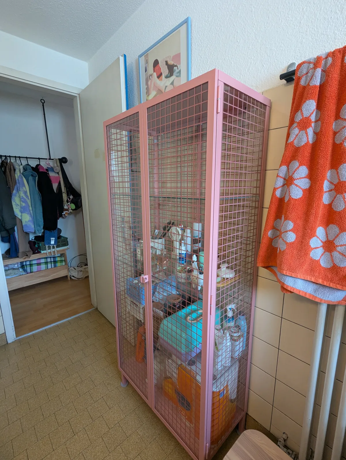 Pink glass cabinet with mesh grid pattern standing in the bathroom.