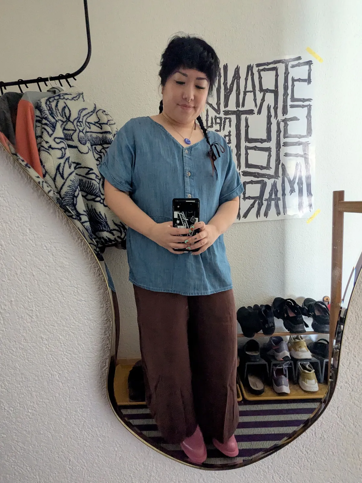 Peige wearing a loose denim top, brown pants, and pink shoes.