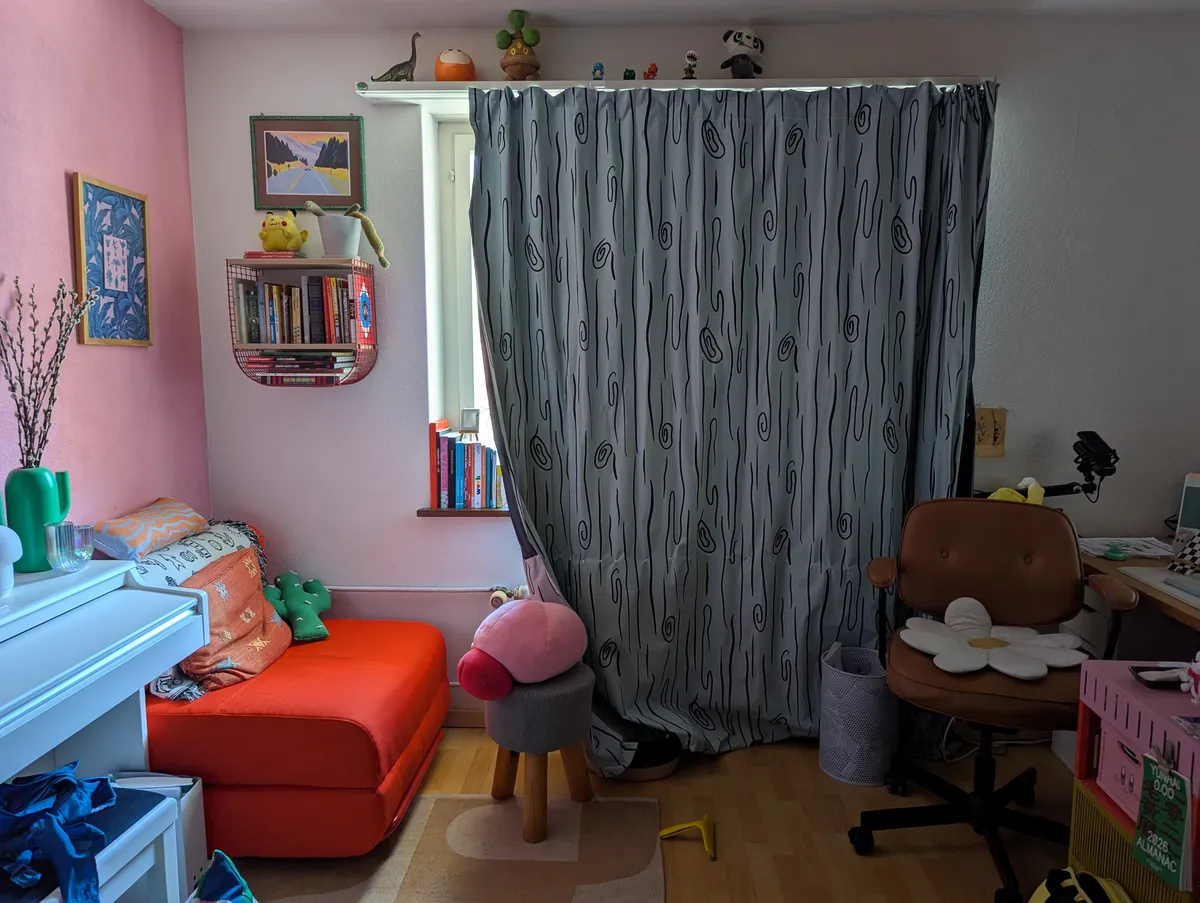 A messy office with curtains drawn.