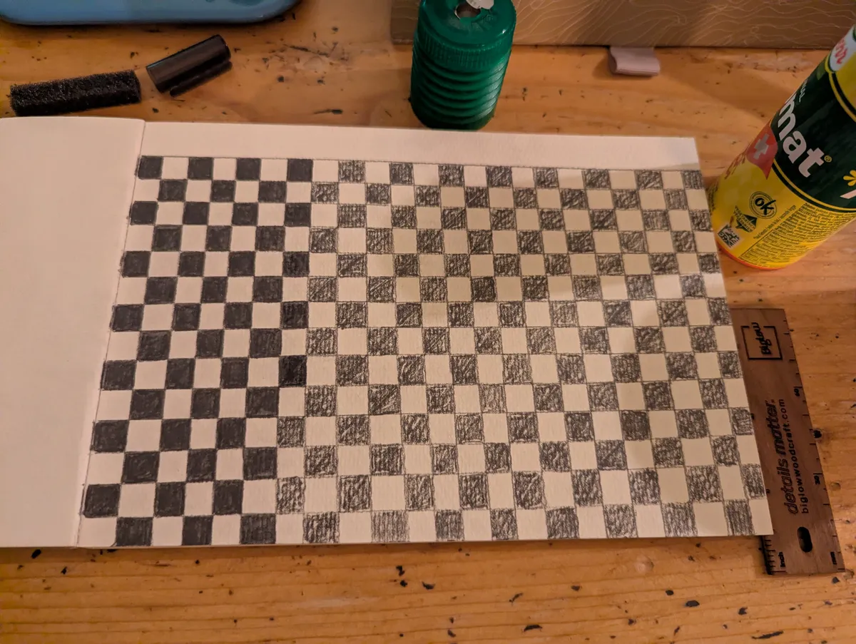 A checkered pattern sketched out in pencil and being painted over in watercolor.