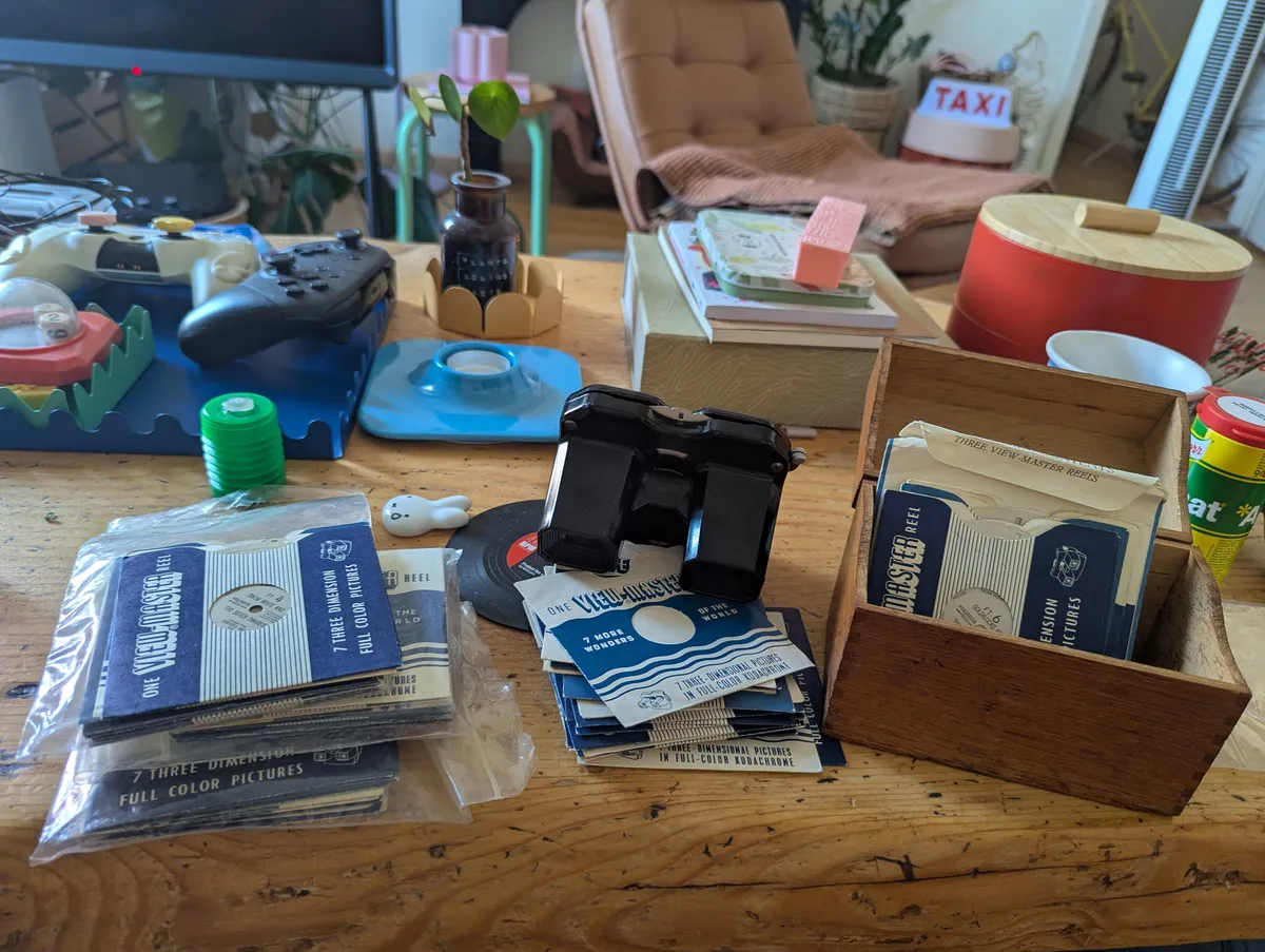 Stacks of Viewmaster film and a black Viewmaster, along with a wooden card box with some film in it.