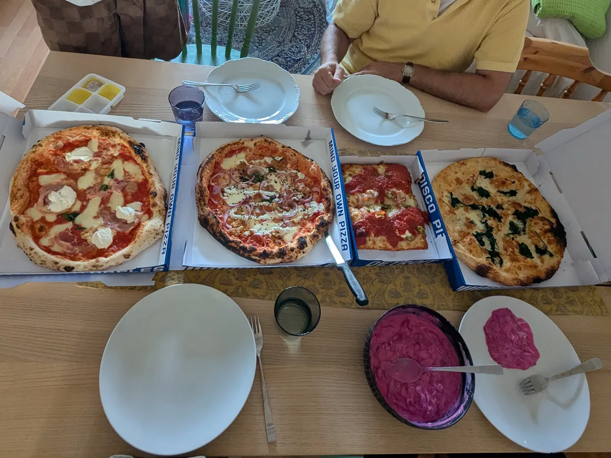 Four different kinds of pizza spread across a dining room table.