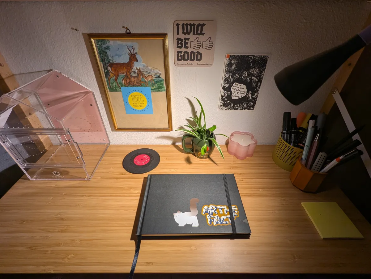 A clean and organized work table with a closed, black sketchbook in the center.