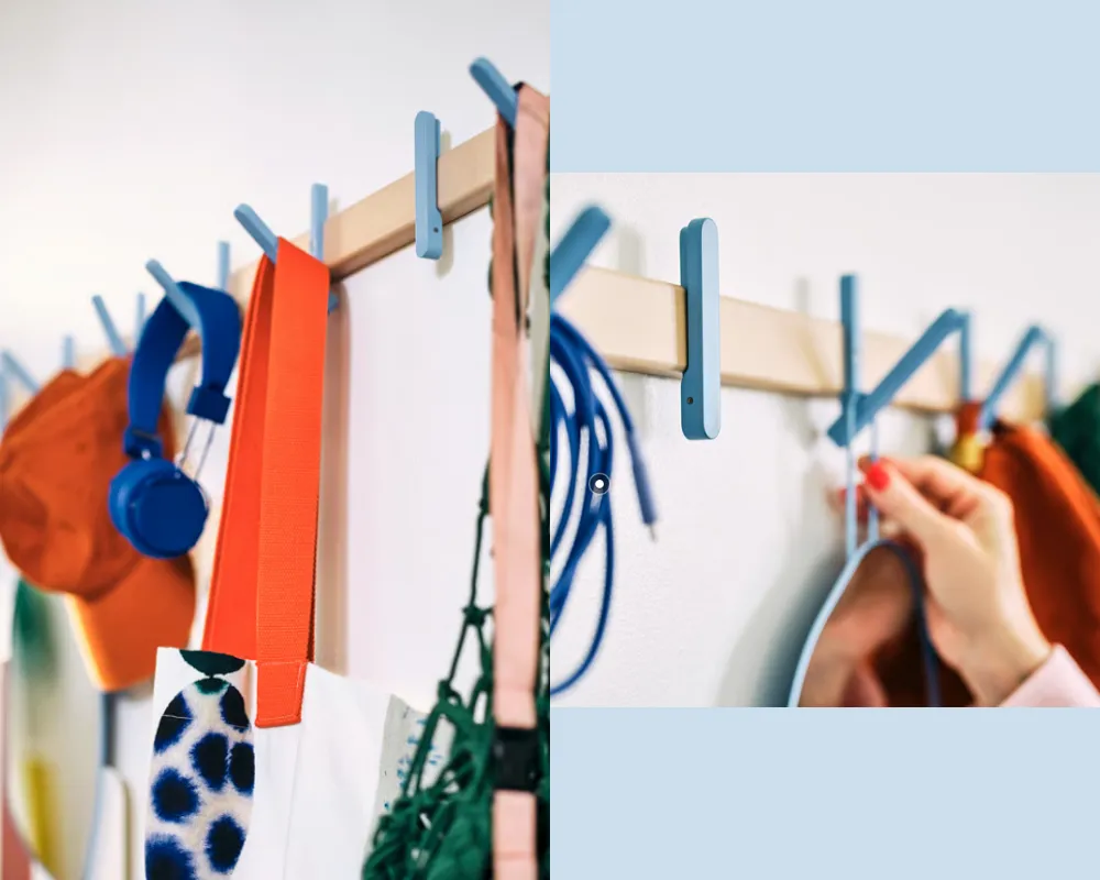 A horizontal rack made of birch. There are pale blue hooks that fold out like a clothes pin attached to the rack.