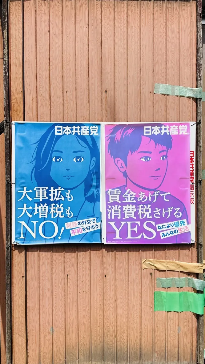 Two political campaign posters are affixed to a wooden board. The left poster features a blue background with a female figure, conveying a message against increased taxes, while the right poster has a pink background with a male figure, advocating for the allocation of funds to support consumption taxes.