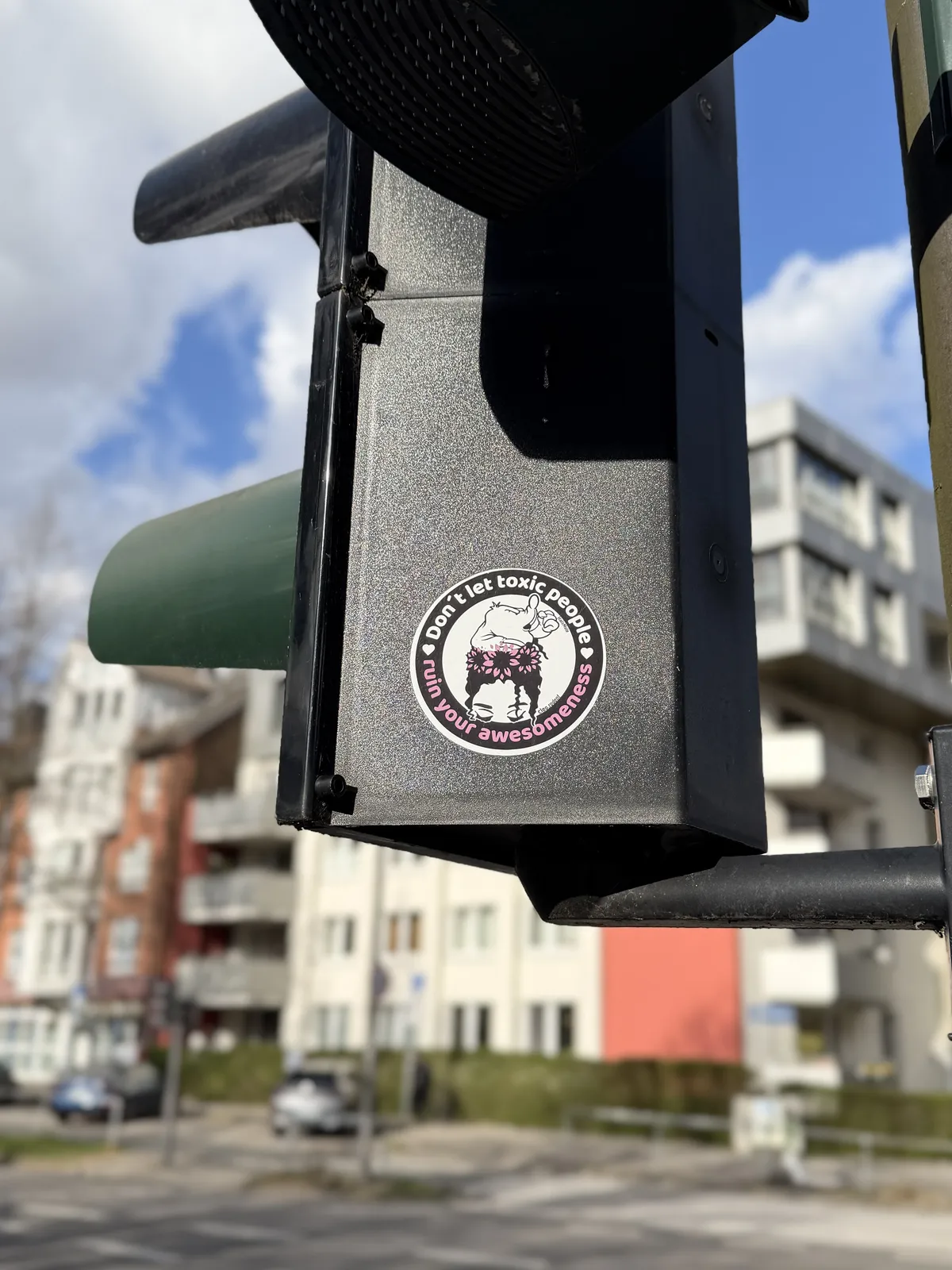 A traffic signal with a sticker that reads 
