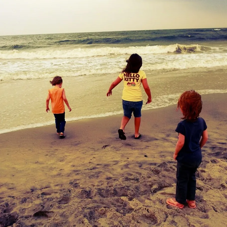 my three daughters on the beach with a vintage filter on it