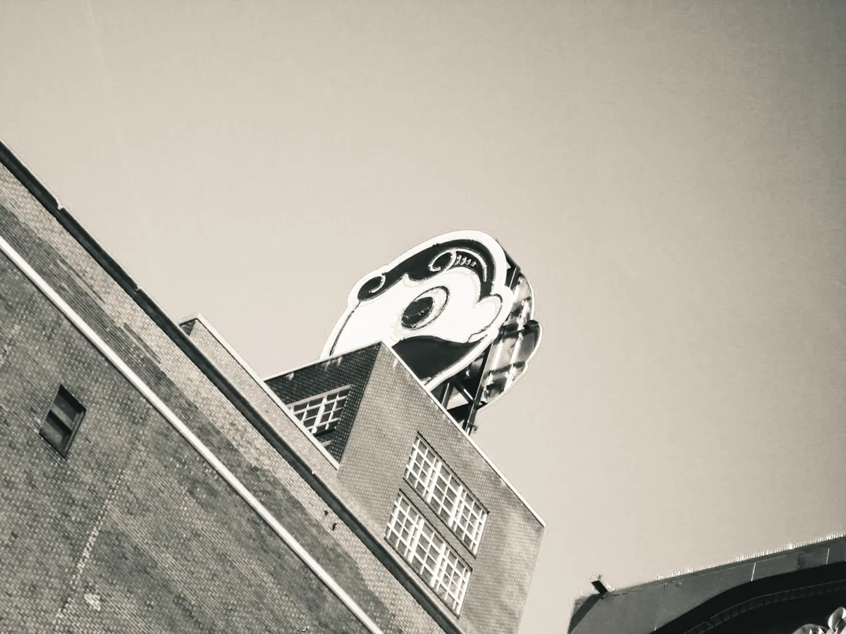 a black and white photo of the Natty Boh guy on top of the Natty Boh building in Baltimore