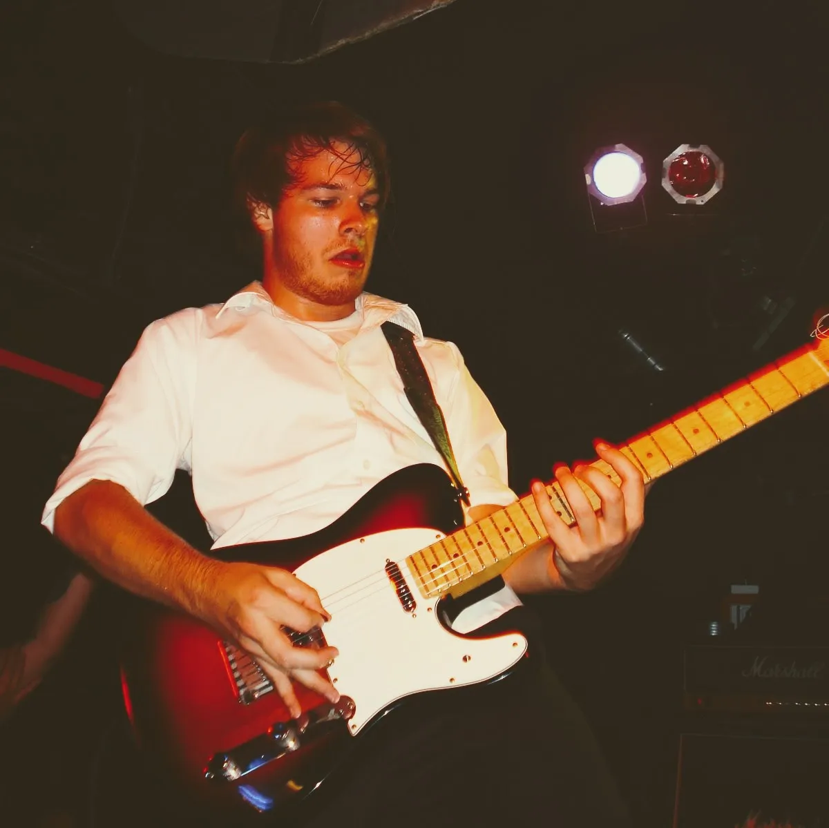 my buddy Chris looking all sweaty wearing a white button up shirt and playing guitar