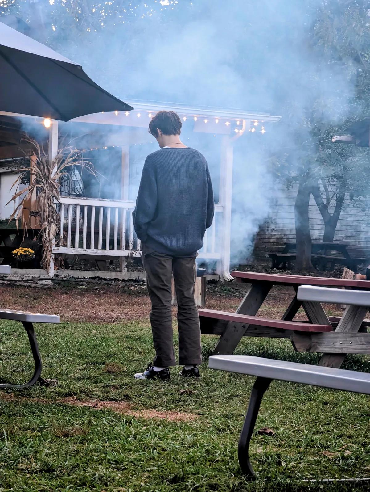 A rando standing in the smoke from a fire pit staring at the ground