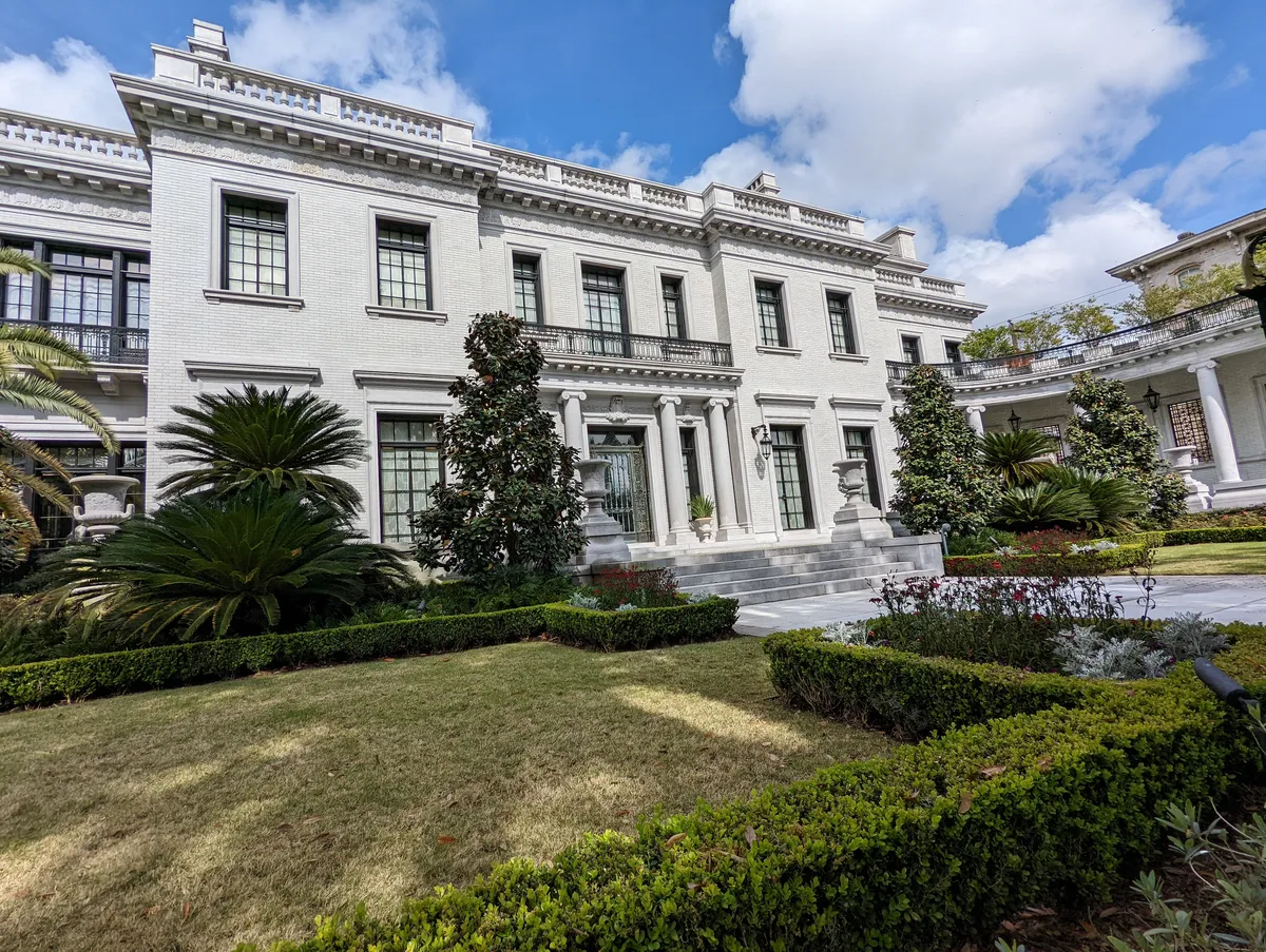 a huge, beautiful white mansion with a manicured lawn