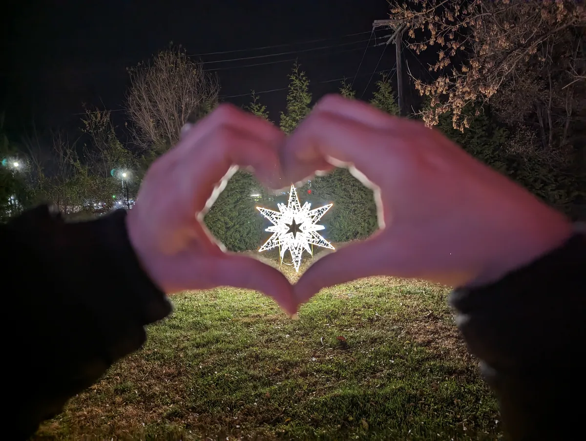 A photo of a lit up star Christmas lawn decision in been my daughters hands in the shape of a heart