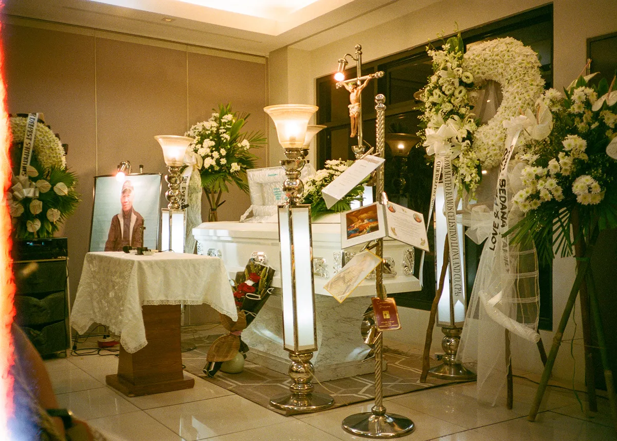 a film photo of my Lolo's coffin and flowers during the wake, taken from the right side at a distance
