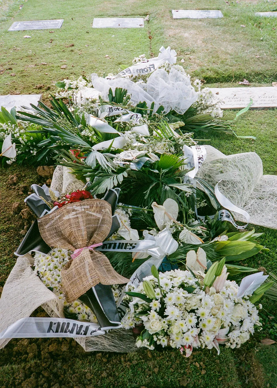 a film photo of flowers, bouquets, and garlands placed on top of my Lolo's burial plot