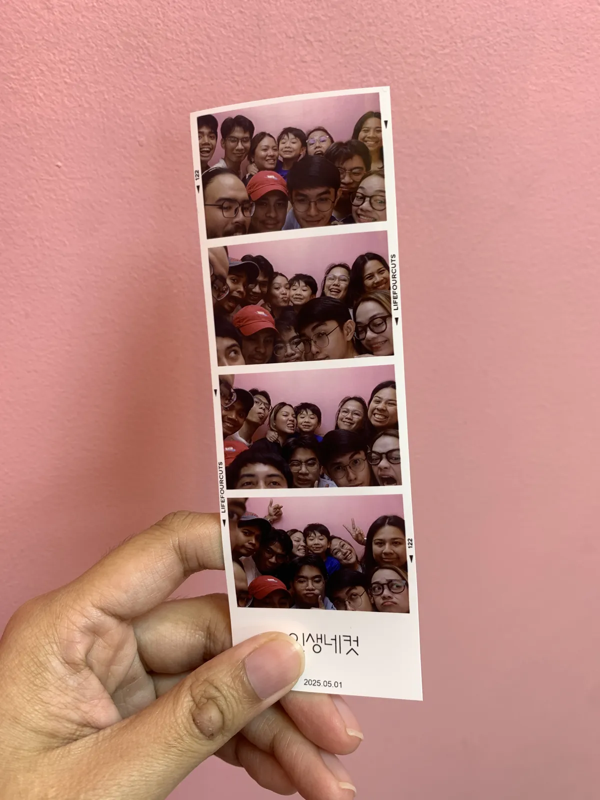 A hand holding a photobooth picture with 11 people on it.