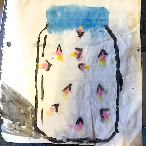 A child's ink and watercolor drawing on wrinkled, off-white paper showing a mason jar filled with fireflies. The jar has a bold black outline and a blue-painted lid, and the interior contains scattered pink and yellow watercolor splotches representing glowing fireflies.