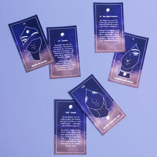 A flat lay shot of 'Taro·Tea' cards showcasing both front and back designs. The cards feature deep blue and purple watercolor gradients with white line-art faces, crescent moons, and text detailing brewing instructions and tea profiles for flavors like sencha, oolong, and pu-erh.
