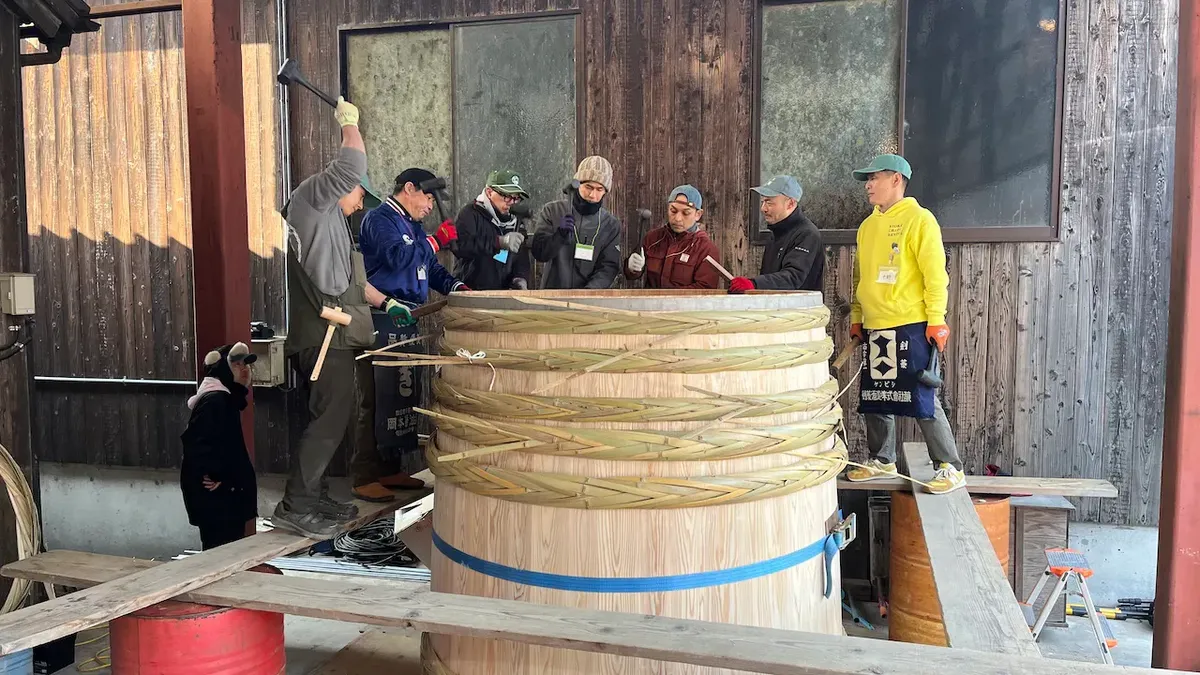 Hammering a bamboo ring that will keep the wooden barrel tight