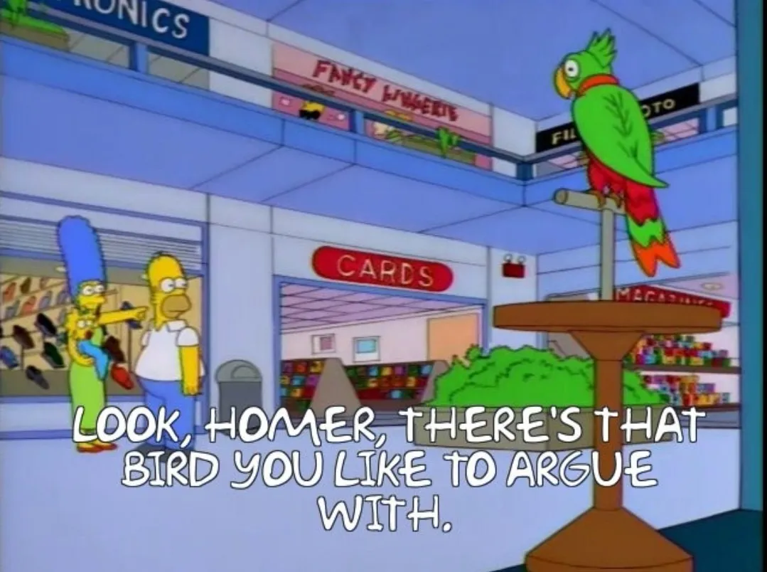 Fonte: série animada Os Simpsons. Quadro de cena em que a família composta por Marge, Homer e Maggie estão no shopping, e Marge aponta pra um passarinho verde e vermelho esbugalhado num puleiro à distância, dizendo “Olha, Homer, tá ali aquele pássaro que tu gosta de brigar.”