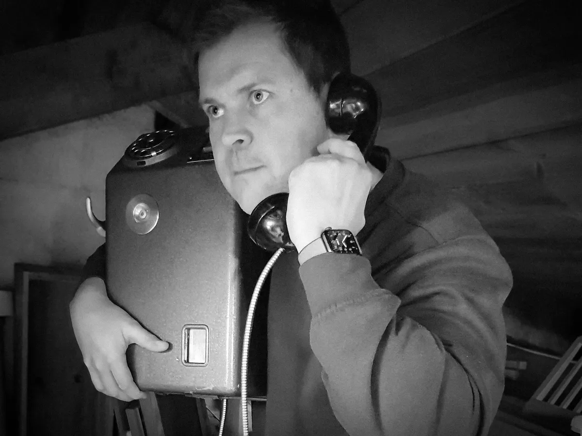 Me in an attic holding a coin payphone