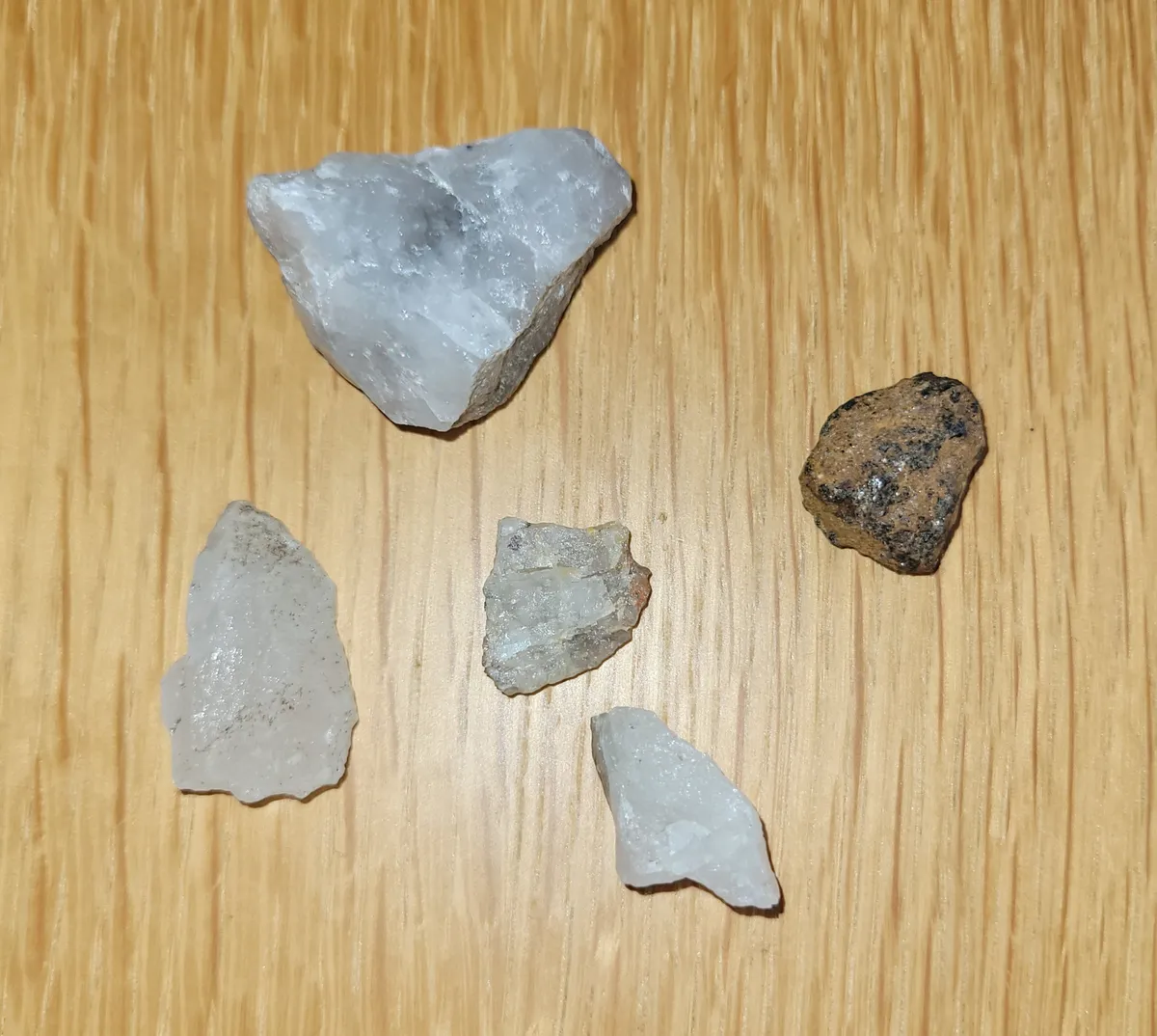 Four pieces of white quartz and a piece of iron ore