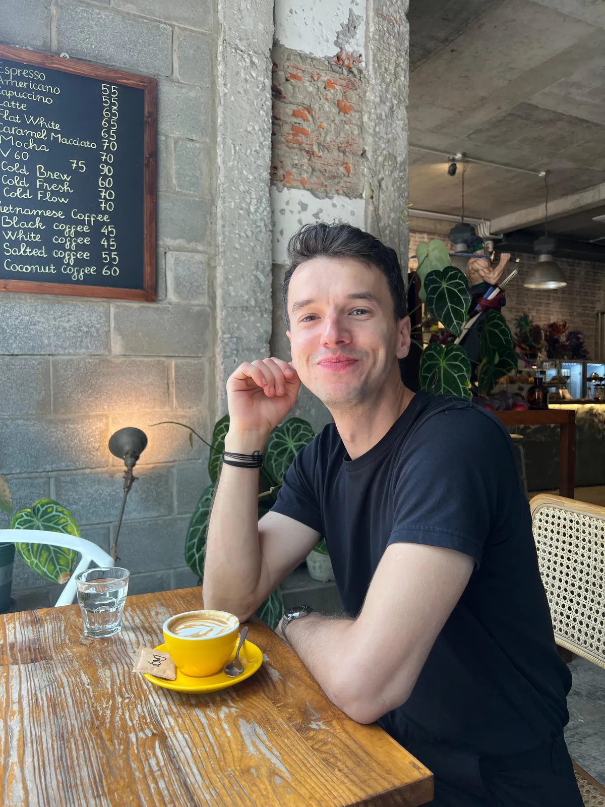 A happy person in a cafe in front of a cup with a delicious flat white