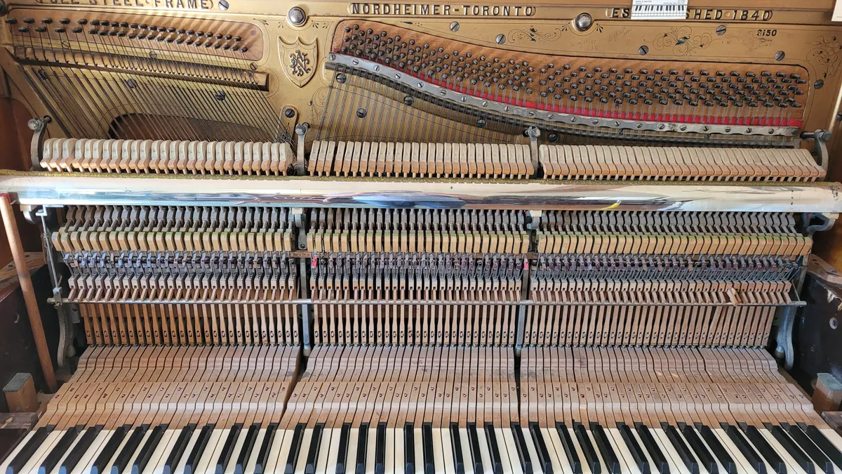 An upright piano with exposed strings