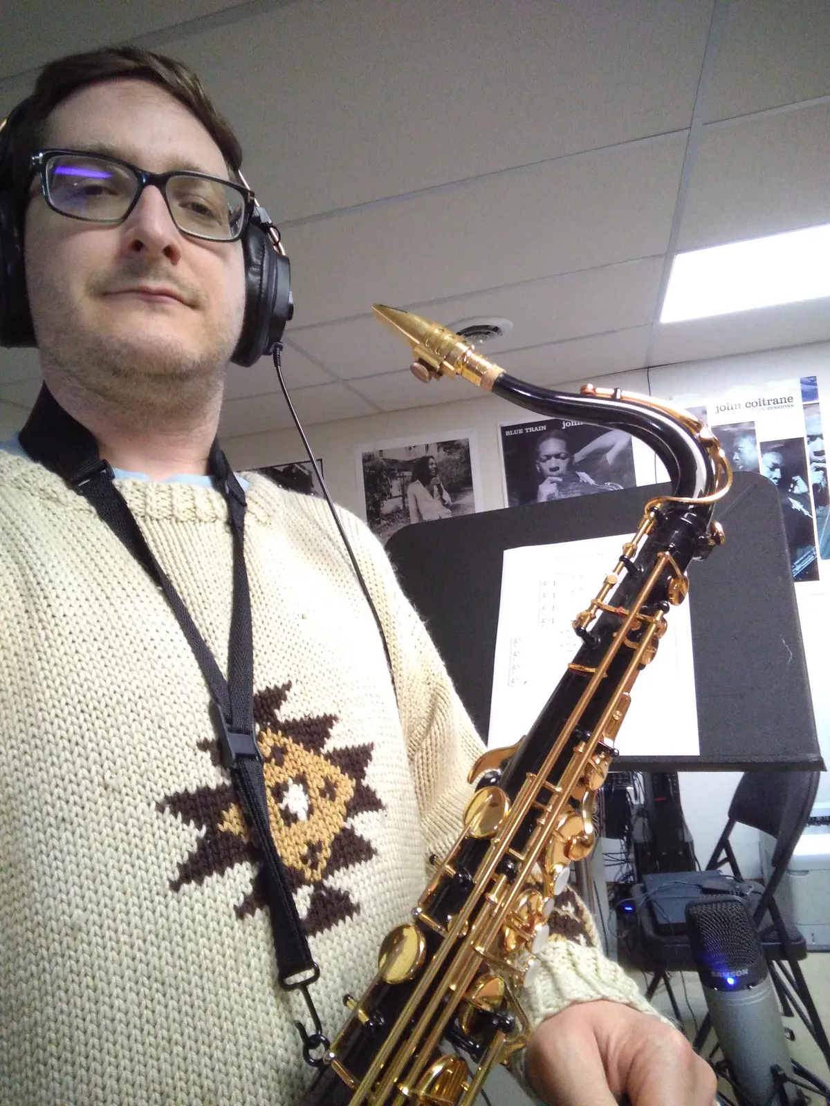 A person wearing headphones and holding a saxophone