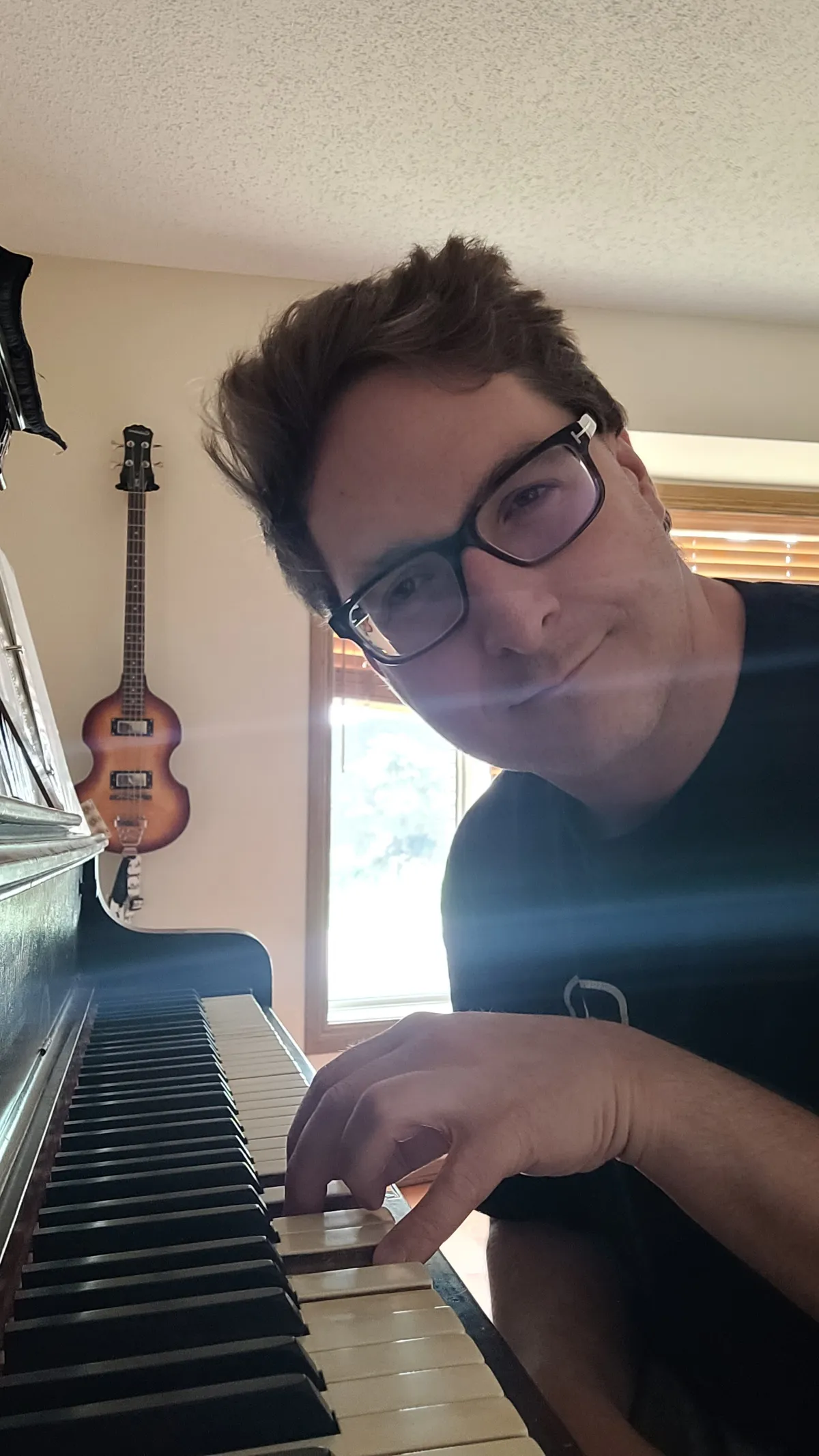 A person at a piano, looking at the camera