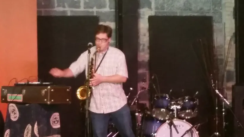 A person playing saxophone and synthesizers on stage