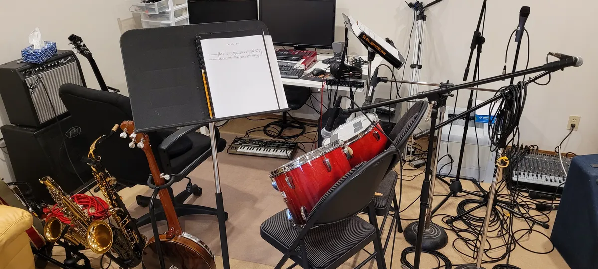 A home studio setup - saxophones, microphones, music stands, amps, drums, keyboards, a banjo, a mixer, and a lot of cables